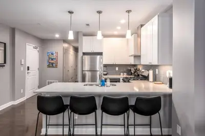 a kitchen with a large white island with black chairs at Soaring 2-Bedroom Parkside Loft Walkable to it All in Cincinnati
