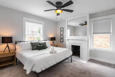 a bedroom with a bed with a ceiling fan and a fireplace at Deluxe 4-Bedroom w Huge Deck 3-Min to Downtown in Cincinnati