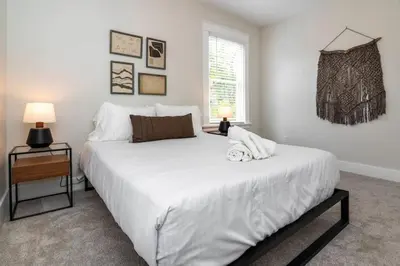 a bedroom with a large white bed and a window at Deluxe 4-Bedroom w Huge Deck 3-Min to Downtown in Cincinnati