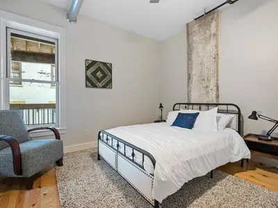 a bedroom with a bed and a chair and a window at Luxury 4-Bedroom Retreat in the Heart of Over the Rhine in Cincinnati