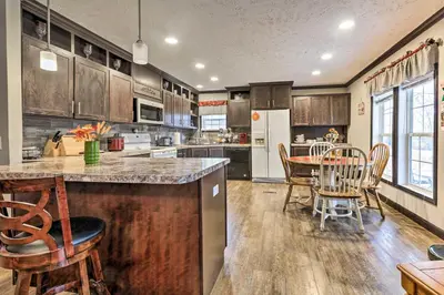 a kitchen with wooden cabinets and a table and chairs at Lovely Sadieville Retreat with Deck and Grill! in Corinth