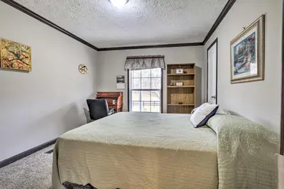 a bedroom with a large bed and a chair at Lovely Sadieville Retreat with Deck and Grill! in Corinth