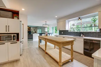 a kitchen with white cabinets and a wooden table at Luxury Maineville Villa with Private Pool and Deck in Maineville