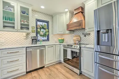 a kitchen with white cabinets and a stainless steel refrigerator at Riverfront Zanesville Getaway with Private Bar! in Dresden