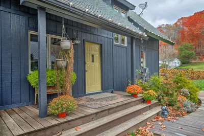 a blue house with a yellow door on a deck at Riverfront Zanesville Getaway with Private Bar! in Dresden
