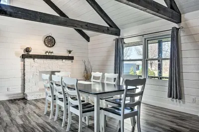 a dining room with a black table and white chairs at Spacious Massillon Log Cabin with Fire Pit! in Massillon