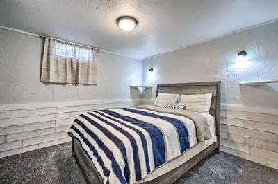 a bedroom with a bed with a striped blanket at Spacious Massillon Log Cabin with Fire Pit! in Massillon