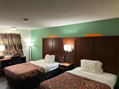 two beds in a hotel room with green walls at Hillcrest Motel by Oyo Aurora near Lawrenceburg in Aurora