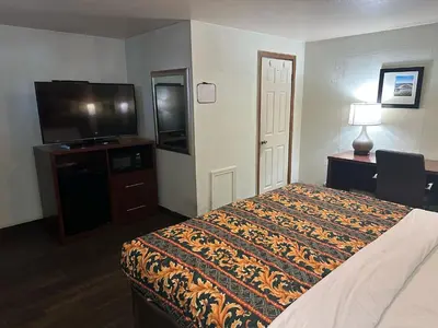 a hotel room with a bed and a flat screen tv at Hillcrest Motel by Oyo Aurora near Lawrenceburg in Aurora