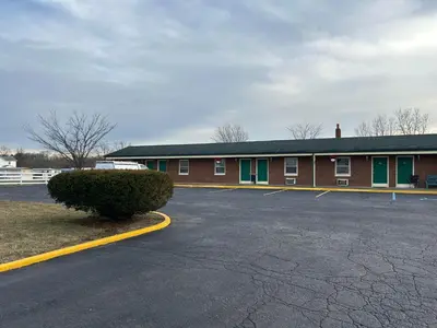 a building with a parking lot in front of it at Hillcrest Motel by Oyo Aurora near Lawrenceburg in Aurora