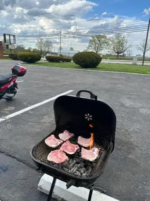 a grill with meat on it in a parking lot at Hillcrest Motel by Oyo Aurora near Lawrenceburg in Aurora