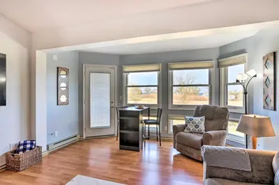 a living room with a desk and chairs and windows at Quaint Couples Escape Pool, Near Lake Erie! in Oak Harbor