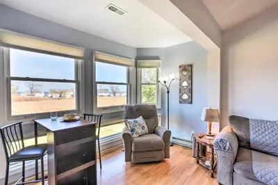 a living room with chairs and a table and windows at Quaint Couples Escape Pool, Near Lake Erie! in Oak Harbor