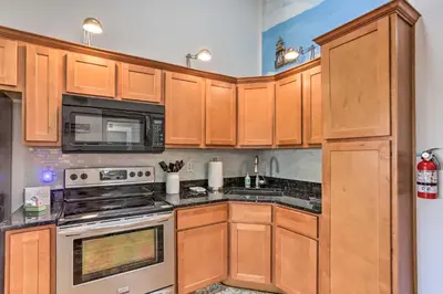 a kitchen with wooden cabinets and a stove top oven at Quaint Couples Escape Pool, Near Lake Erie! in Oak Harbor