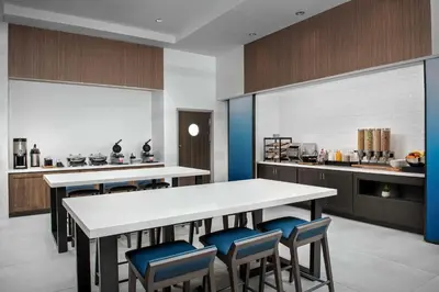 a kitchen with a white table and blue chairs at Hilton Garden Inn Florence Cincinnati Airport South in Florence