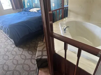 a bathroom with a bath tub next to a bed at DELUXE INN in Erie