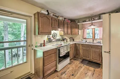a kitchen with wooden cabinets and a stove top oven at Riverside Cabin with 3 Decks in North Vernon! in North Vernon