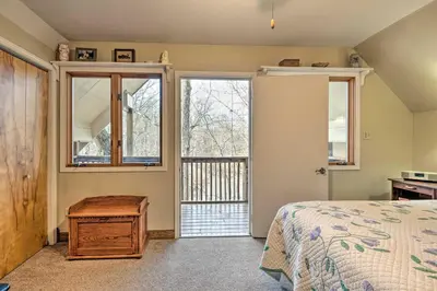 a bedroom with a bed and a door to a balcony at Riverside Cabin with 3 Decks in North Vernon! in North Vernon