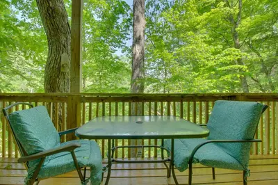 a table and chairs on a deck with trees at Riverside Cabin with 3 Decks in North Vernon! in North Vernon