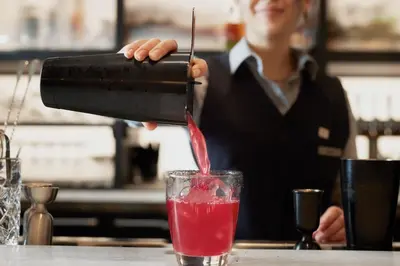 a woman pouring a red drink into a glass at AC Hotel by Marriott Dayton in Dayton