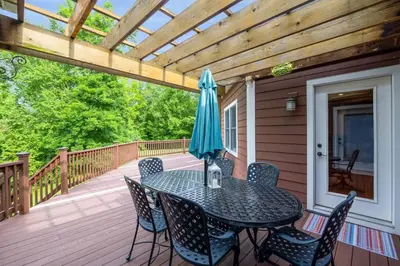 a table with chairs and an umbrella on a deck at 5755 Butler Warren Cheerful 6-Bedroom Villa with fishing pond in Jericho