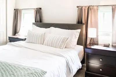 a bedroom with a bed with white sheets and a lamp at The Penthouse- Heart of OTR w/Rooftop Terrace in Cincinnati
