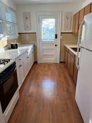 a kitchen with wooden floors and a white refrigerator at Hunter #1, Private One Bed near Xavier & Downtown in Bellevue