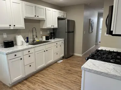 a kitchen with white cabinets and a stainless steel refrigerator at Wilson Two Bedroom House in Historic Loveland in Loveland