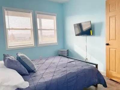 a blue bedroom with a bed and a flat screen tv at Housepitality - The Bliss Lodge - Large House in Columbus