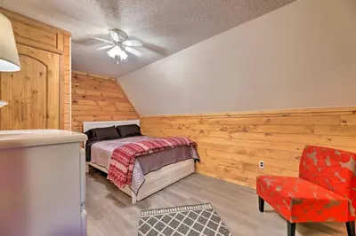 a bedroom with wooden walls and a bed and a chair at Cozy Yatesville Lake Cabin Rental in Louisa! in Louisa