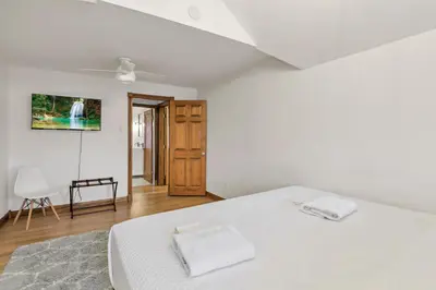 a white bedroom with a bed and a chair at Updated 4BD House Near German Village w Parking in Columbus
