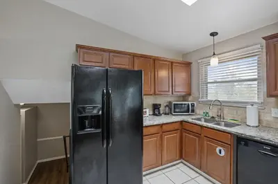 a kitchen with a black refrigerator and wooden cabinets at Housepitality - The Woodward Park Charmer - 4BR in Columbus
