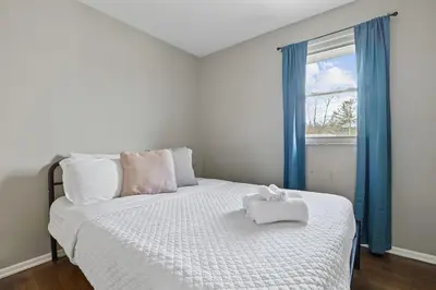 a bedroom with a white bed with blue curtains and a window at Housepitality - The Woodward Park Charmer - 4BR in Columbus