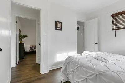 a white bedroom with a bed and a hallway at Housepitality - The Southern Orchards Cottage in Columbus