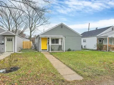 a house with a yellow door in a yard at Housepitality - The Southern Orchards Cottage in Columbus