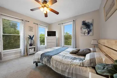 a bedroom with a bed with a ceiling fan and windows at The Village Townhouse - 5 BR in Columbus