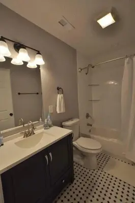 a bathroom with a sink and a toilet and a mirror at Housepitality - Franklinton Farmhouse- 4 Bedrooms in Columbus