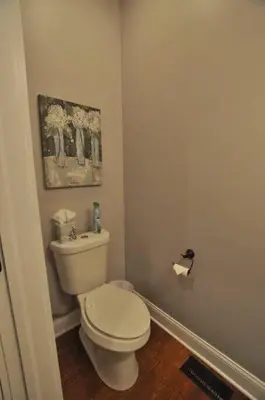 a bathroom with a toilet and a painting on the wall at Housepitality - Franklinton Farmhouse- 4 Bedrooms in Columbus