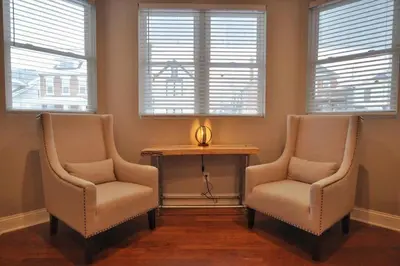 two chairs and a table in a room with windows at Housepitality - Franklinton Farmhouse- 4 Bedrooms in Columbus