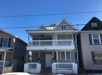 a large house with a balcony on the front of it at Housepitality - Franklinton Farmhouse- 4 Bedrooms in Columbus