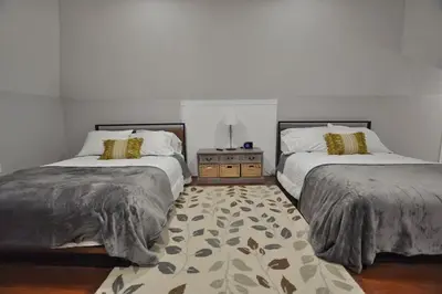 a bedroom with two beds and a rug at Housepitality - Franklinton Farmhouse- 4 Bedrooms in Columbus