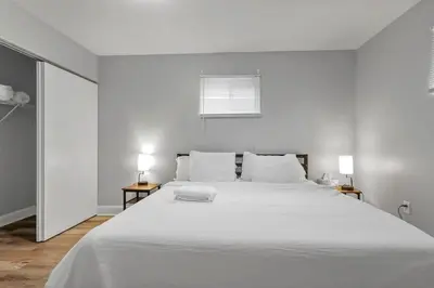 a white bedroom with a large white bed with two lamps at German Village Hidden Gem - 3 BR, Parking l Value in Columbus