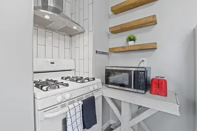 a white kitchen with a stove and a microwave at Housepitality - Newark Friends and Family House in Newark