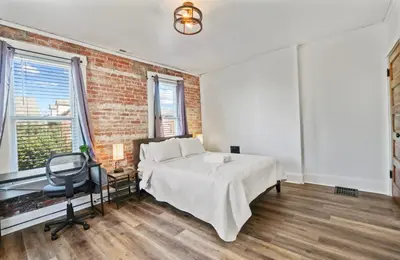 a bedroom with a bed and a desk and a chair at Housepitality - City View Loft - German Village in Columbus