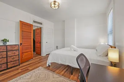 a bedroom with a bed and a table and a chair at Housepitality - Cityscape - Historic 2BR in Columbus