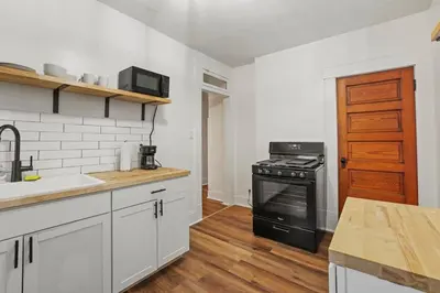 a kitchen with white cabinets and a black stove at Housepitality - Cityscape - Historic 2BR in Columbus