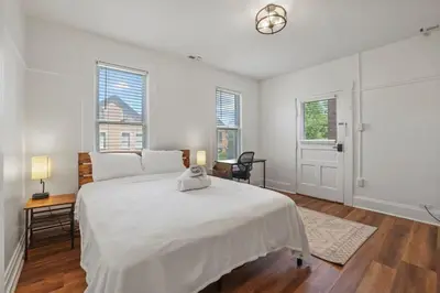a white bedroom with a large bed and windows at Housepitality - Cityscape - Historic 2BR in Columbus