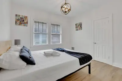 a white bedroom with a large bed and a chandelier at Housepitality- The 614 Peaceful Escape - Old Town in Columbus