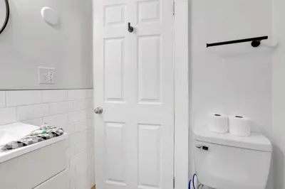 a white bathroom with a toilet and a white door at Housepitality- The 614 Peaceful Escape - Old Town in Columbus