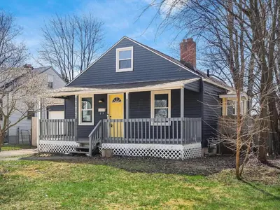 a black house with a porch with a yellow door at The Lucky 7's Inn-5 Beds in Columbus